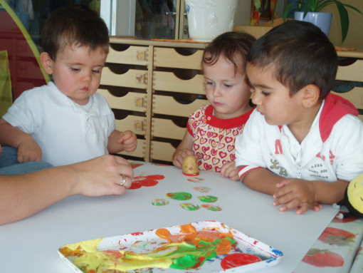 Drei Kinder gestalten, gemeinsam mit ihrer Pädagogin, kreativ mit Kartoffeln als Stämpel