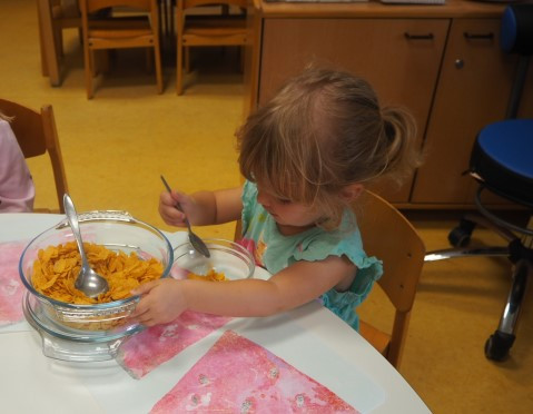 Ein Mädchen frühstückt konzentriert Cornflakes