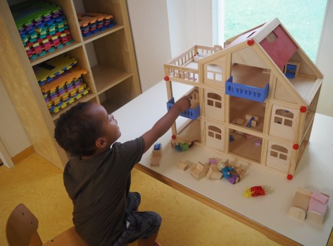 Ein Junge gestaltet ein hölzernes Puppenhaus