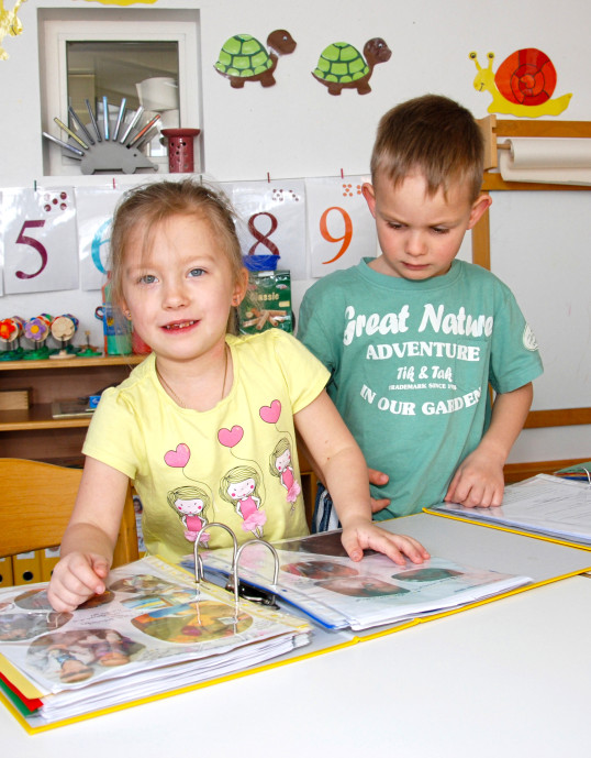 Mädchen und Bub betrachten Portfoliomappe