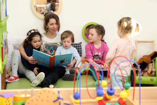 Pädagogin liest mit Kindern aus einem Buch