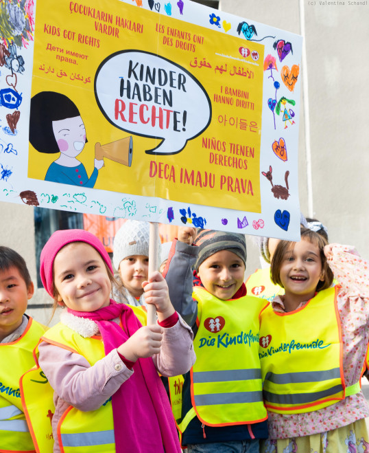 Kinder lachen und halten Schild hoch: Kinder haben Rechte!