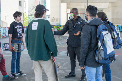 Drei Mitarbeiter*innen des Fair-Play-Teams reden mit Skateboardern