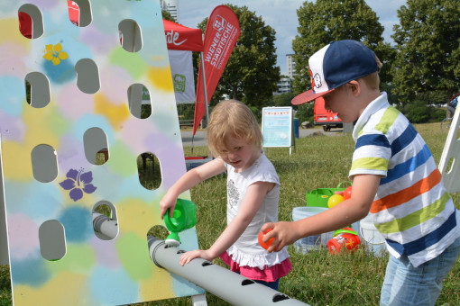 Zwei Kinder spielen mit Wasserspielzeug bei Regenrinne