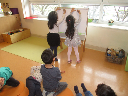 Kinder präsentieren ihr Kunstwerk auf einer Tafel im Gruppenraum