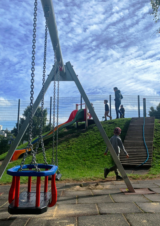Ein Kind im Garten mit Schaukel, Rutsche und Kletterseil