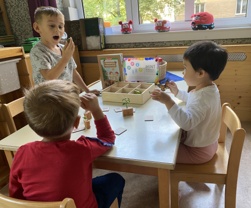 Kinder beschäftigen sich im Gruppenraum mit einem Kartenspiel