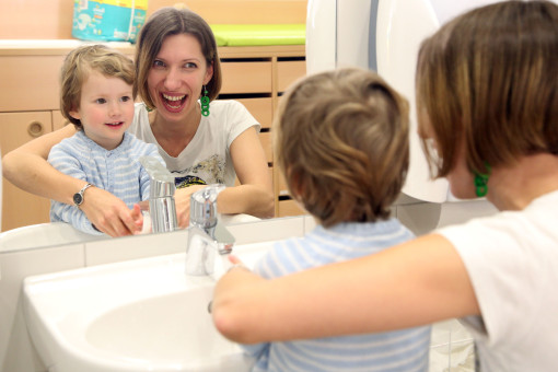 Pädagogin wäscht Hände mit Kind