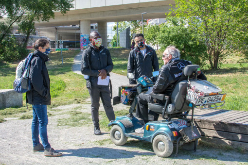 Drei Mitarbeiter*innen des Fair-Play-Teams reden mit einem Mann im Rollstuhl 