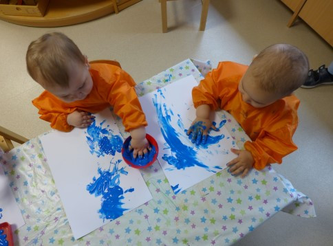 Kleinkinder malen auf Papier mit Fingerfarben