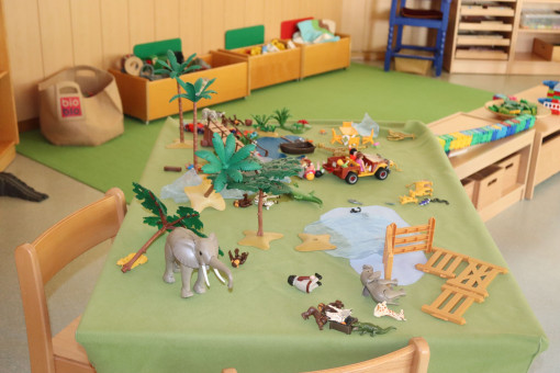 Einblick in den Gruppenraum - Tisch ist gedeckt mit Tieren, Pflanzen, etc.