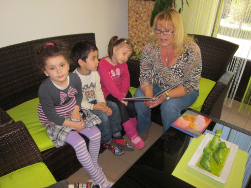 Eine Pädagogin ließt drei Kindern ein Buch vor 