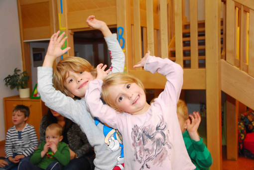 Zwei Kinder werfen die Arme hoch