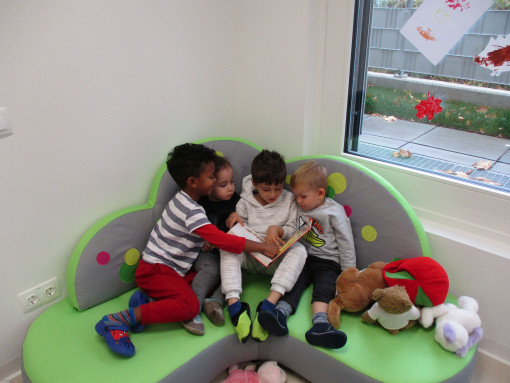 4 Kinder beschäftigen sich mit einem Buch im Lesebereich