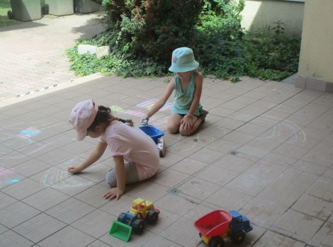 Zwei Mädchen gestalten kreativ mit Malkreide im Außenbereich