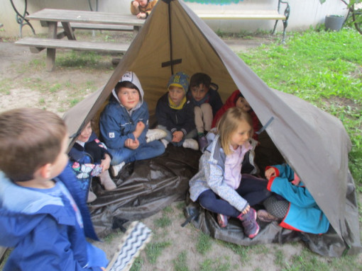 Kinder sitzen gemeinsam in einem Zelt im Garten
