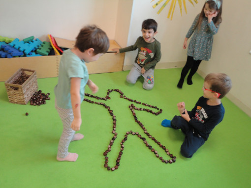 4 Kinder legen eine Figur mit Kastanien
