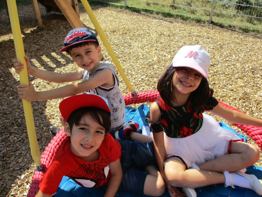 3 Kinder sind auf der Schaukel im Garten