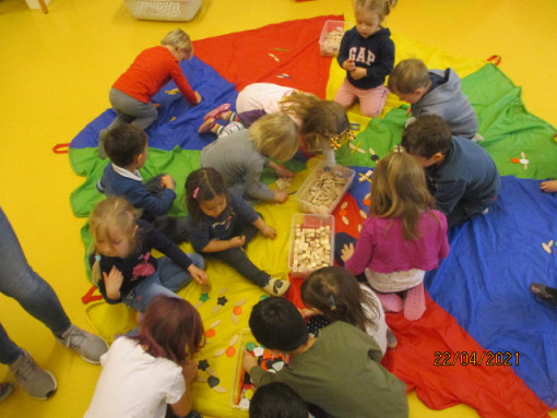 Kinder konstruieren gemeinsam mit Holz auf einem bunten Tuch