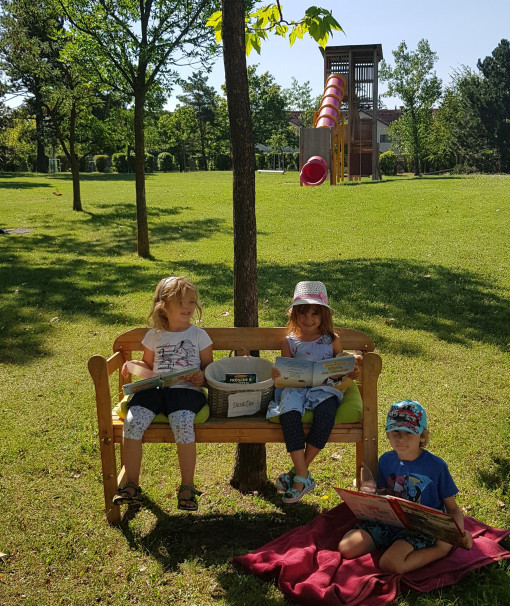 Kinder sitzen mit Jause im Park