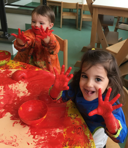 2 Kinder färben Schüsseln rot mit sehr viel Fingerfarbe auf den Händen