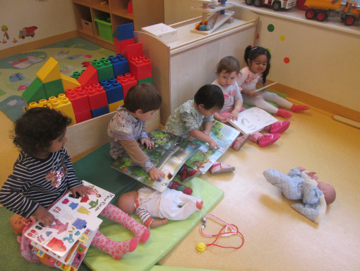 Fünf Kinder sitzen im Lesebereich und beschäftigen sich mit Bilderbüchern