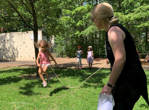 Pädagogin und Kinder im Garten üben mit der Springschnur springen