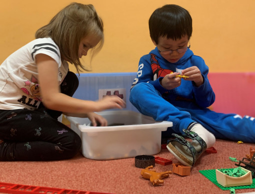 Zwei Kinder bauen mit Lego und Tieren