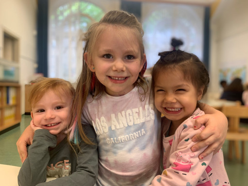 Drei Kinder stehen lächelnd im Gruppenraum