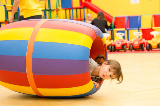 Mädchen liegt in einem bunten Spielfass 