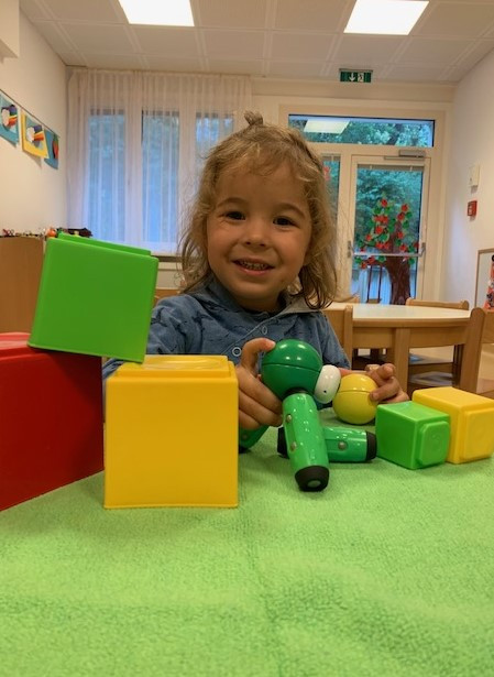 Ein Mädchen baut lächelnd mit verschiedenen Bausteinen