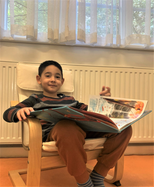 Ein Bub liest im Lesebereich ein Buch