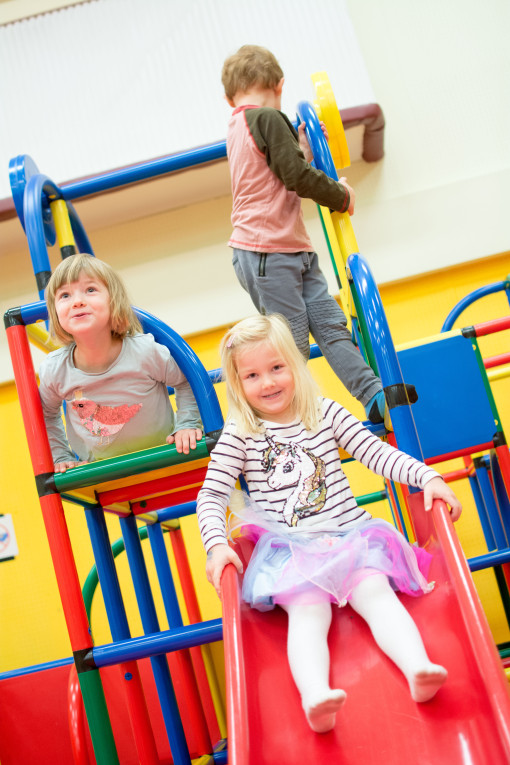 Drei Kinder klettern auf einem Spielgerüst