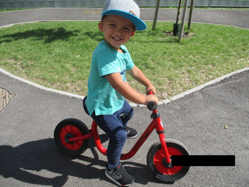 1 Kind fährt auf einem Laufrad im Garten