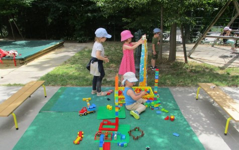 Kinder bauen ein Duplogebäude im Garten