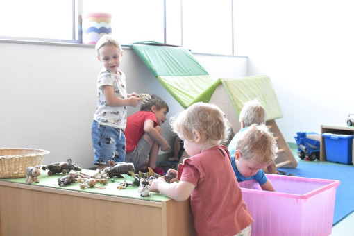 Kinder konstruieren gemeinsam ein Haus aus Matten und andere betrachten Tierfiguren