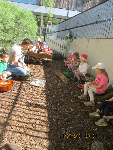 Eine Kindergruppe forscht gemeinsam im Garten mit dem Pädagogen