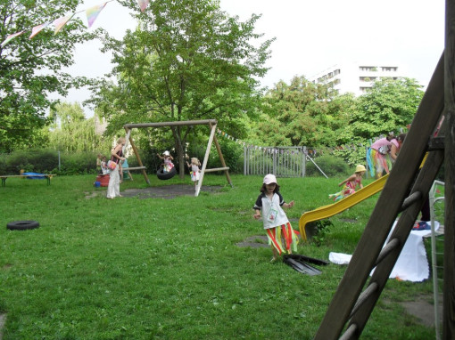 Einige Kinder spielen gemeinsam im weitläufigen und üppig begrünten Garten