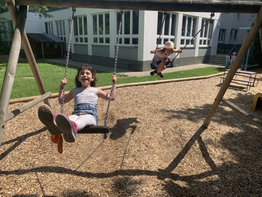 Zwei Kinder schaukeln im Garten