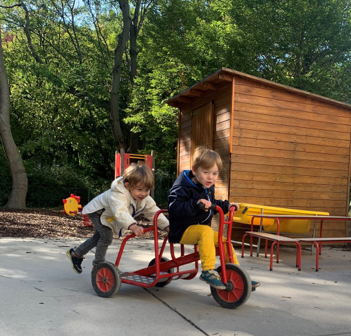 Zwei Kinder fahren mit dem Tretfahrrad im Garten