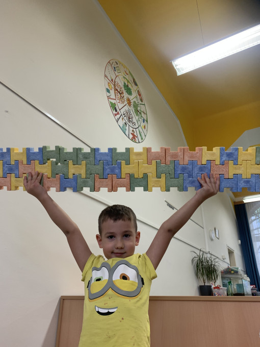 Ein Kind hält Moosgummisteine hoch, die in einer Reihe zusammengesteckt sind