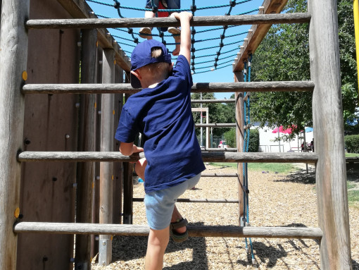 Ein Junge klettert konzentriert auf einem Klettergerüst