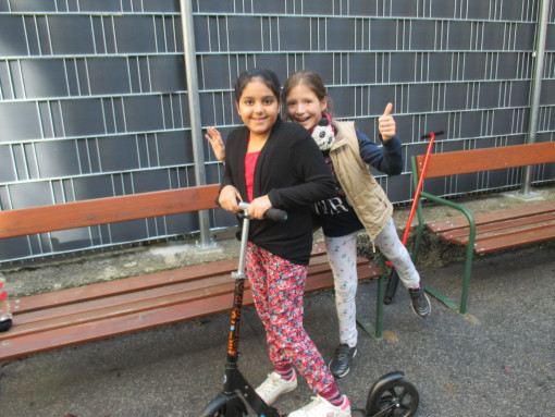Zwei Mädchen auf Roller im Hof