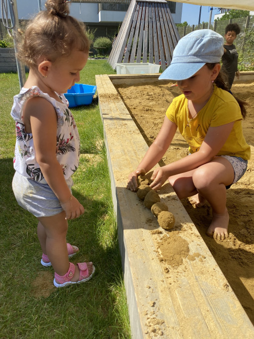 Zwei Kinder formen bei der Sandkiste Sandkugeln