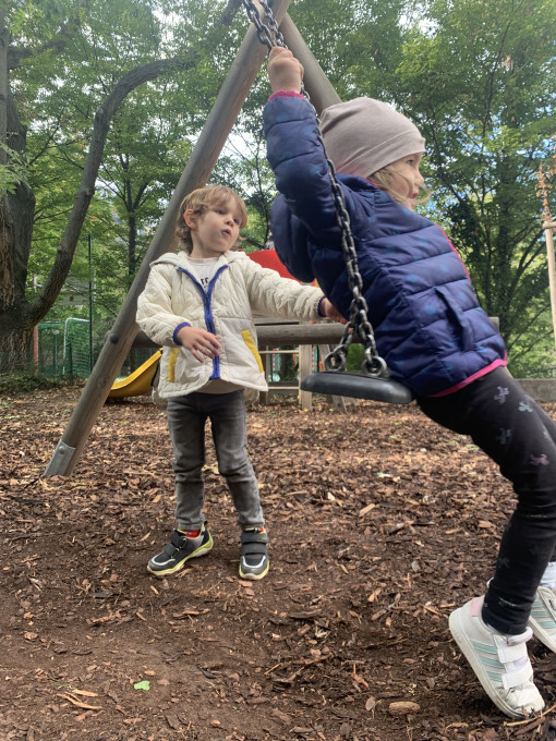 Zwei Kinder bei der Schaukel im Garten