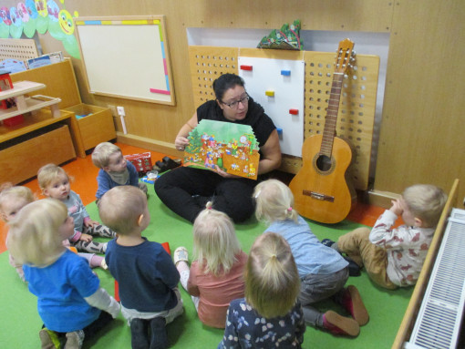 Kinder und Pädagogin sehen sich gemeinsam ein Buch an