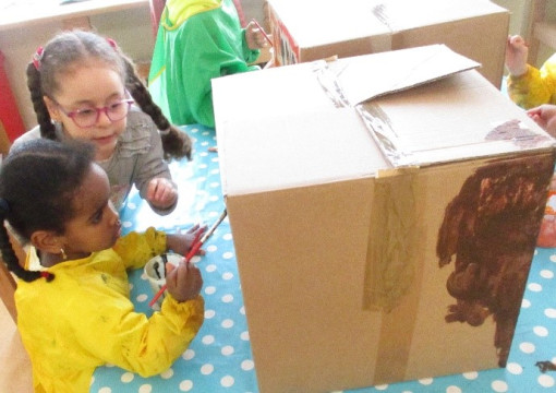 Zwei Kinder basteln mit einer großen Schachtel
