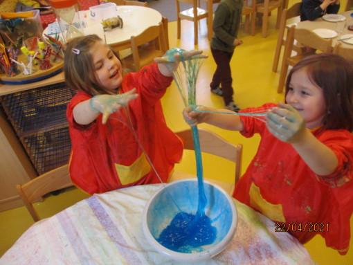 Zwei Mädchen experimentieren gemeinsam mit einer schleimigen blauen Masse