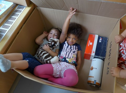Kinder liegen gemeinsam in einem großen Karton 
