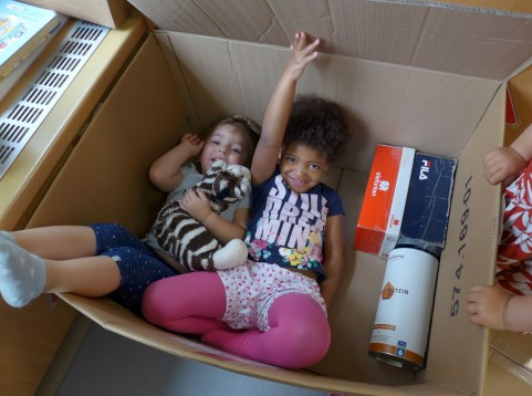 Kinder liegen gemeinsam in einem großen Karton